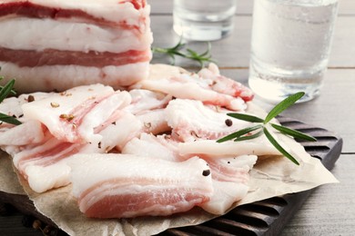 Photo of Tasty salt pork with rosemary and spices on wooden table, closeup