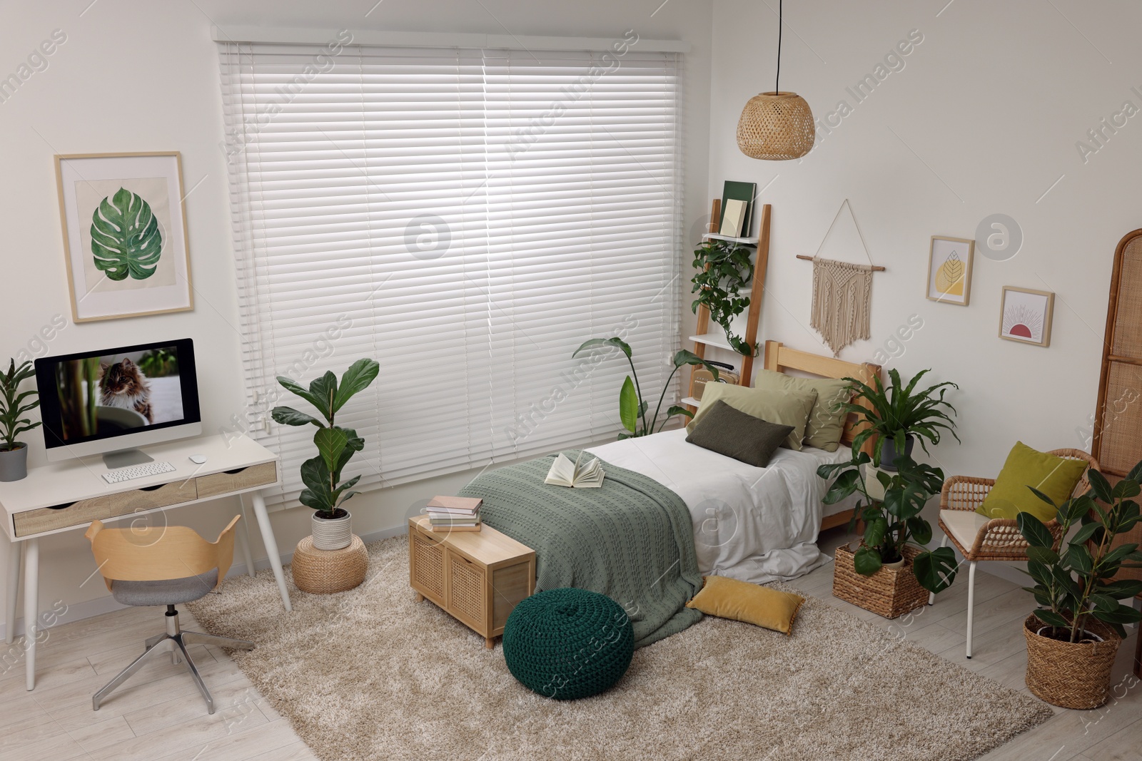 Photo of Comfortable bed, desk with computer and potted houseplants in stylish bedroom. Interior design