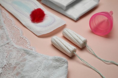 Photo of Woman's panties, menstrual pad, cup and tampons on peach background