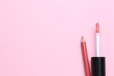 Photo of Bright lip pencil and brush of liquid lipstick on pink background, flat lay with space for text. Cosmetic products