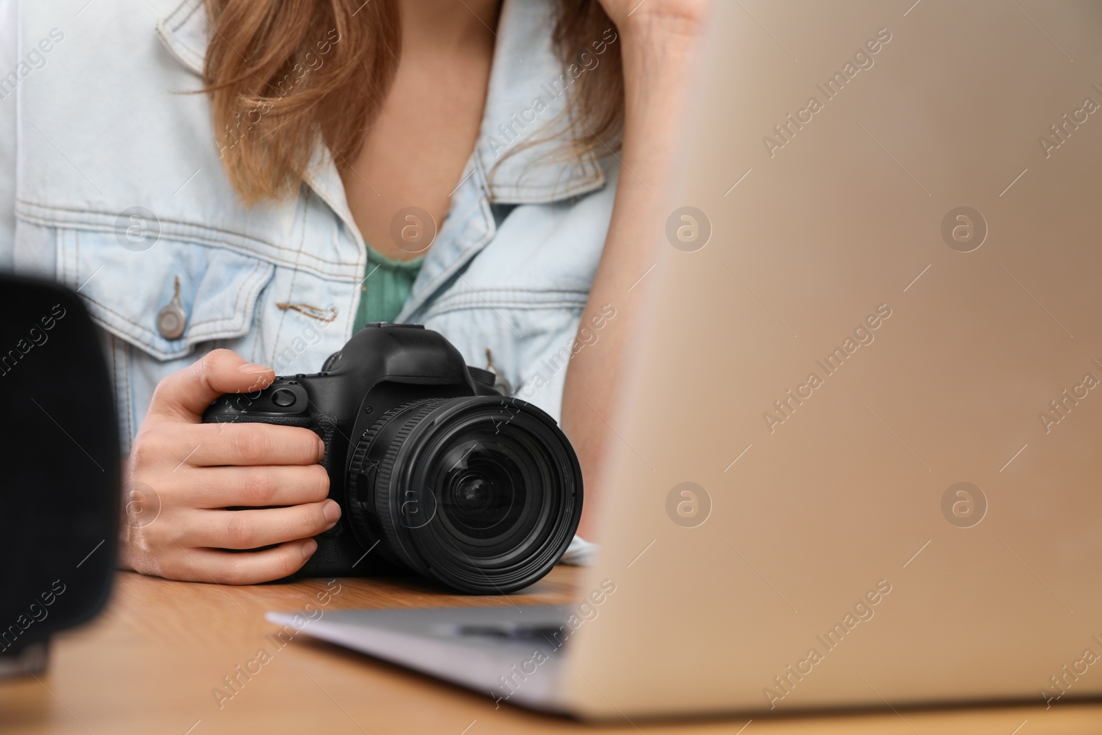 Photo of Professional photographer with camera working at table in office, closeup