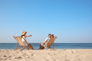 Young couple relaxing in deck chairs on beach