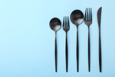 Stylish cutlery set on light blue table, flat lay. Space for text