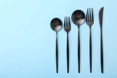 Photo of Stylish cutlery set on light blue table, flat lay. Space for text