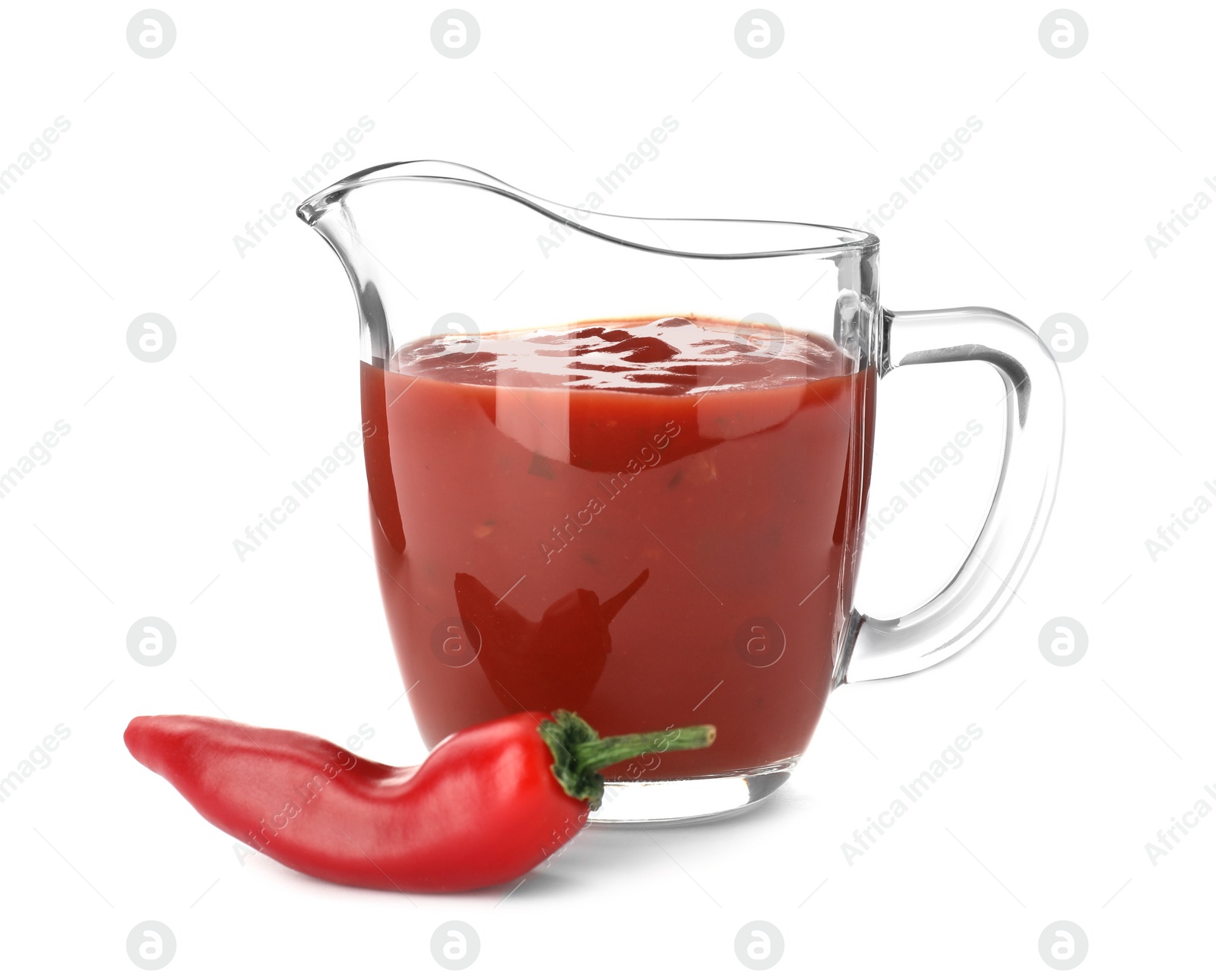 Photo of Jug with spicy chili sauce and fresh pepper on white background