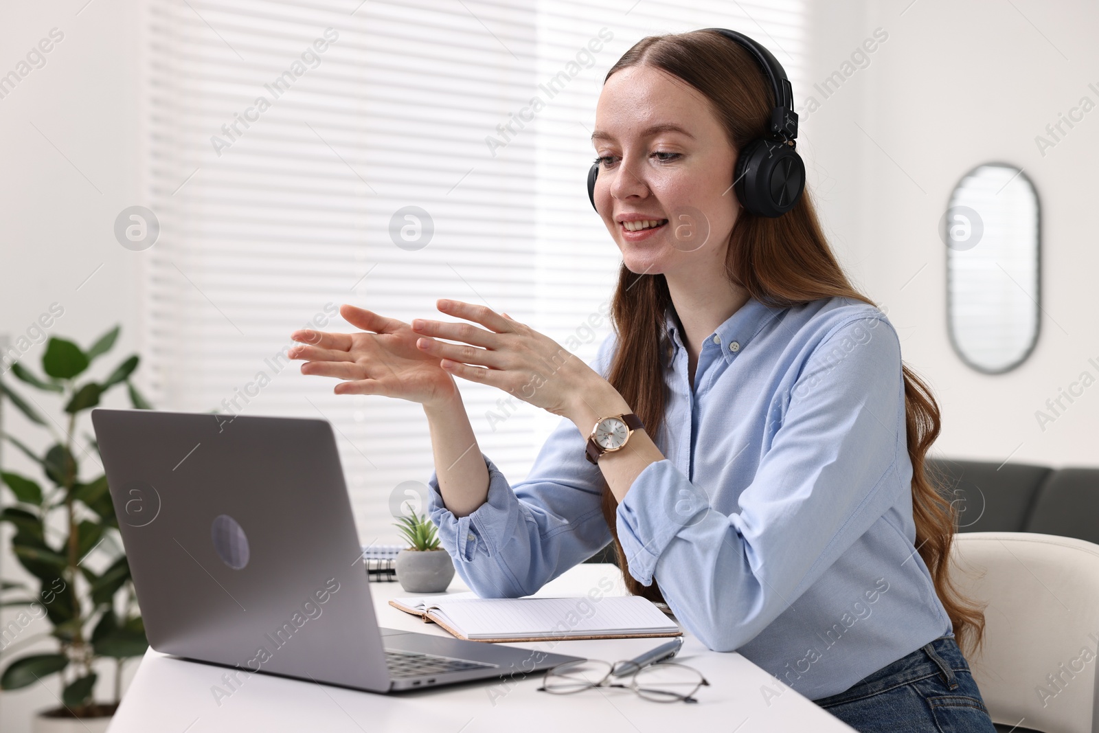 Photo of E-learning. Young woman using laptop during online lesson at white table indoors