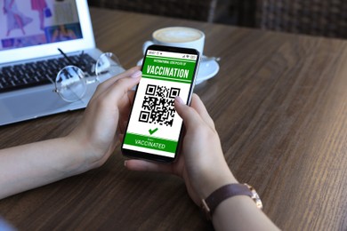 Woman holding smartphone with international certificate of vaccination indoors, closeup