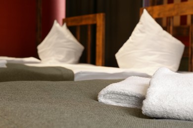 Photo of Clean folded towels on bed in hotel room. Space for text