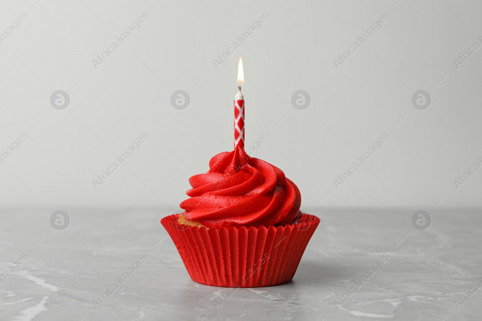 Photo of Delicious birthday cupcake with cream and burning candle on marble table