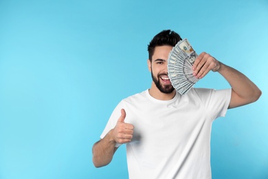 Portrait of happy young man with money on color background. Space for text