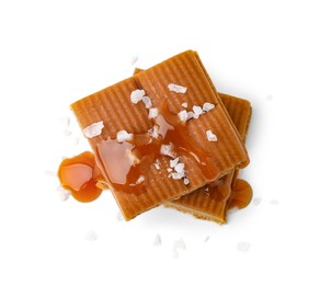 Photo of Yummy caramel candies and sea salt isolated on white, top view