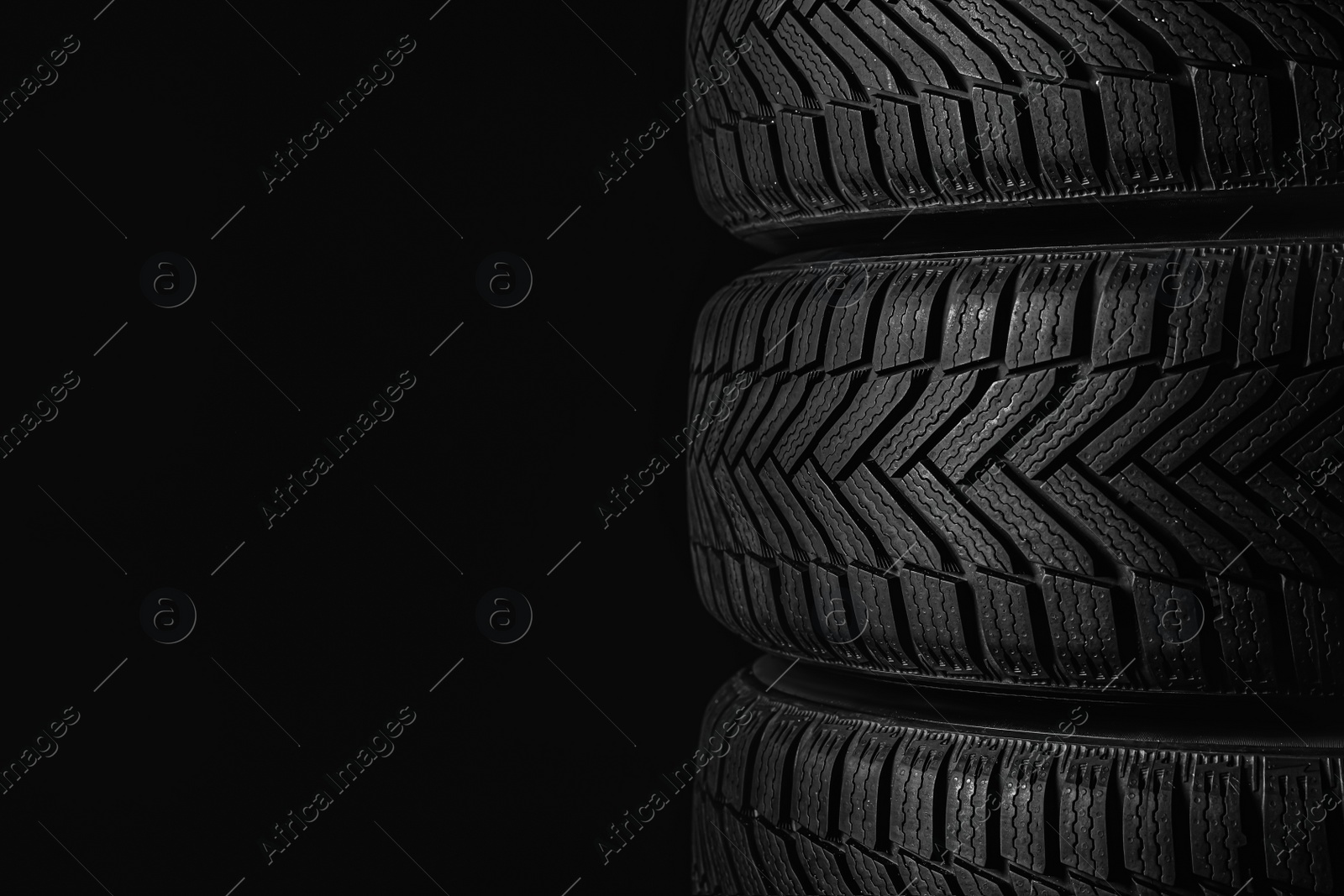 Photo of Winter tires on black background, closeup. Space for text