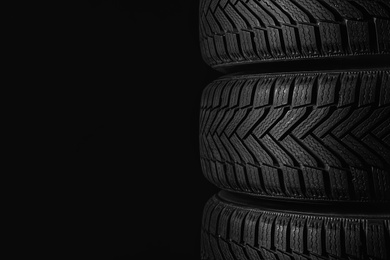 Winter tires on black background, closeup. Space for text
