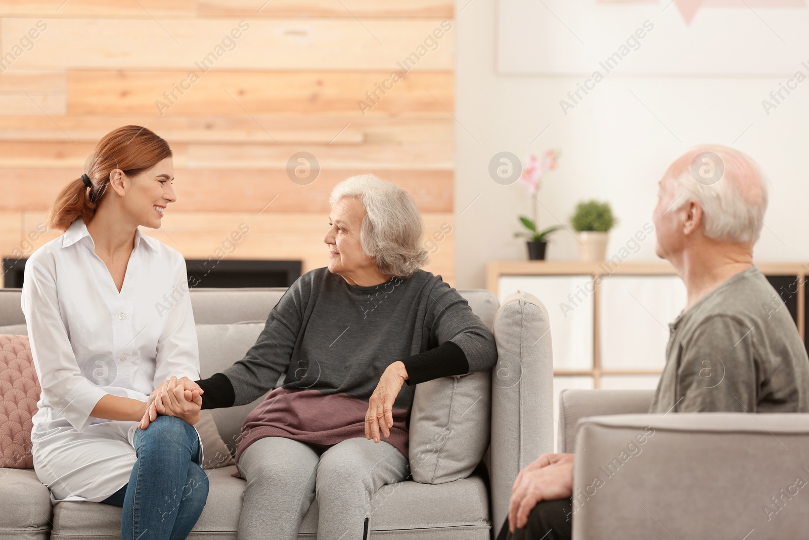 Photo of Elderly spouses with female caregiver in living room