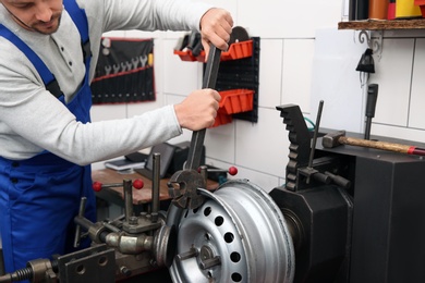 Mechanic working with car disk lathe machine at tire service, closeup