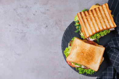 Tasty sandwiches served on grey table, top view. Space for text