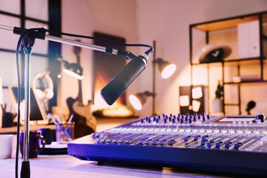 Photo of Microphone near table with professional mixing console in radio studio