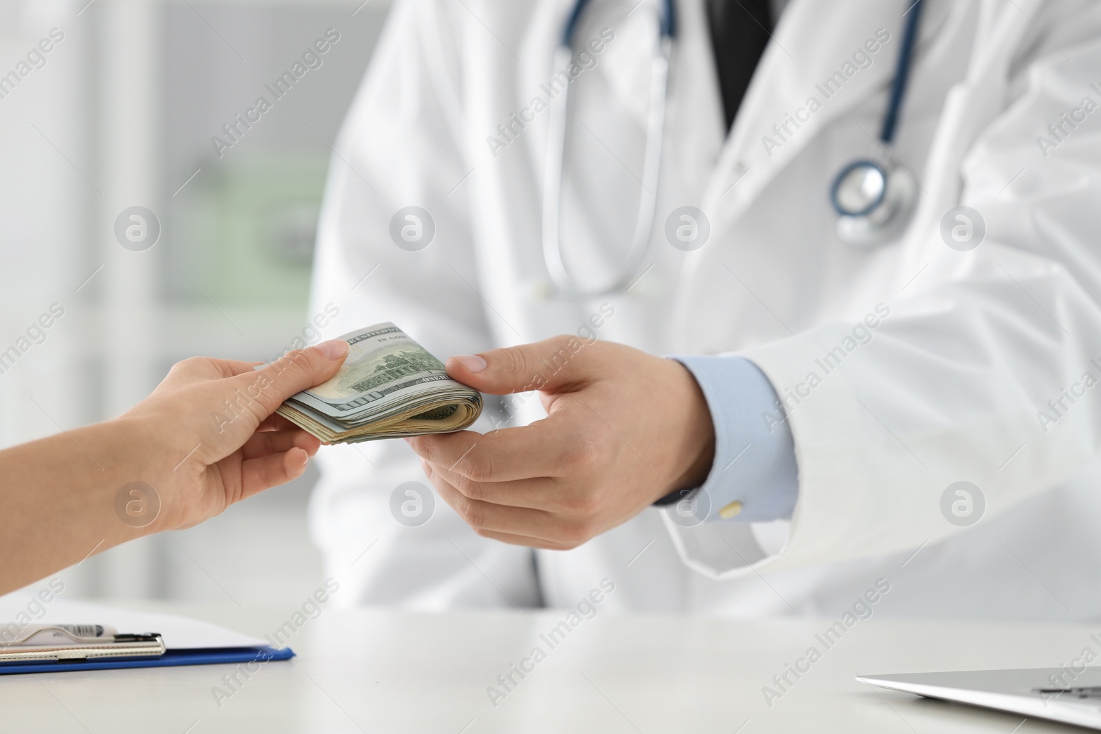 Photo of Patient giving bribe to doctor in clinic, closeup. Corrupted medicine