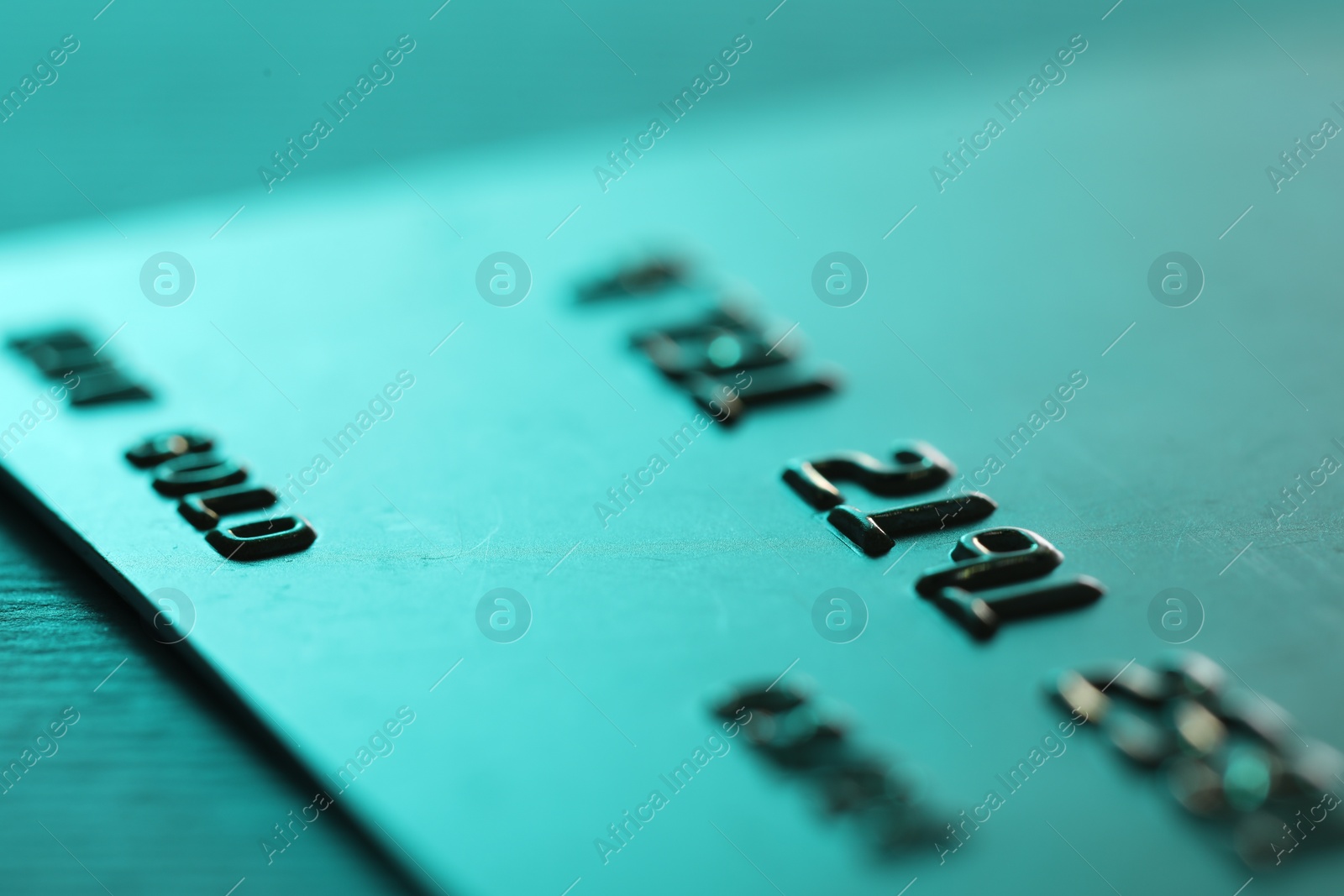 Photo of One credit card on turquoise background, macro view