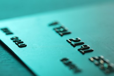 Photo of One credit card on turquoise background, macro view