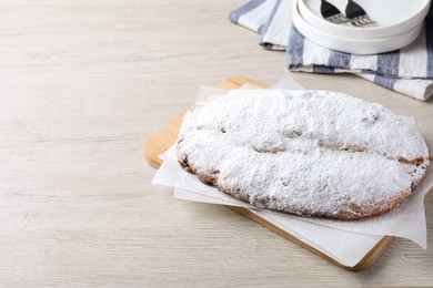 Photo of Delicious Stollen sprinkled with powdered sugar on wooden table, above view. Space for text