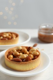 Photo of Tartlets with caramelized nuts on white wooden table, space for text. Tasty dessert