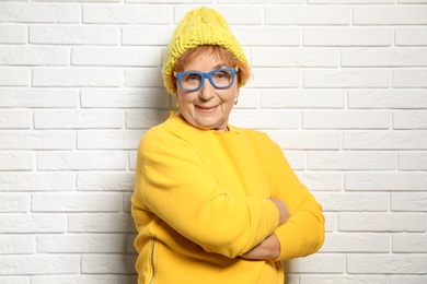 Photo of Portrait of elderly woman in hipster outfit near brick wall