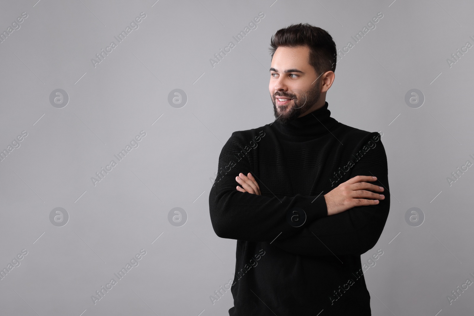 Photo of Happy man in stylish black sweater on grey background, space for text