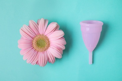 Flat lay composition with menstrual cup and gerbera flower on color background. Gynecological care