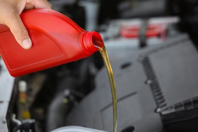 Photo of Man pouring motor oil from red container, closeup. Space for text