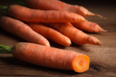 Photo of Ripe fresh carrot on wooden table, closeup