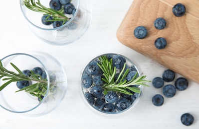 Flat lay composition with blueberry and rosemary cocktail on light table