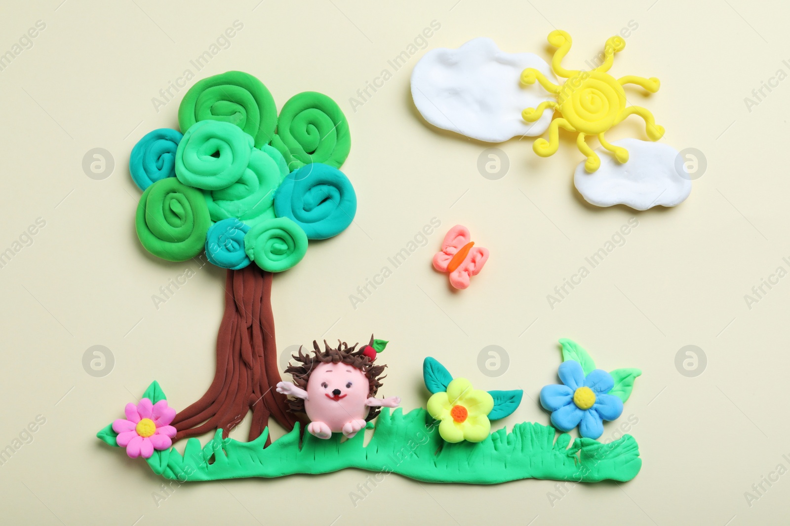 Photo of Colorful tree, hedgehog, sun and flowers made with play dough on beige background, flat lay