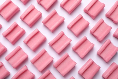 Photo of Tasty pink chewing gums on white background, flat lay