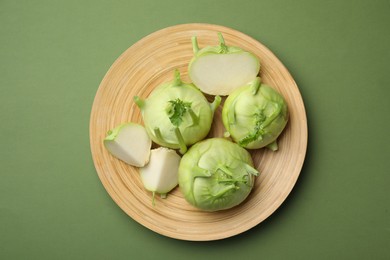Whole and cut kohlrabi plants on green background, top view