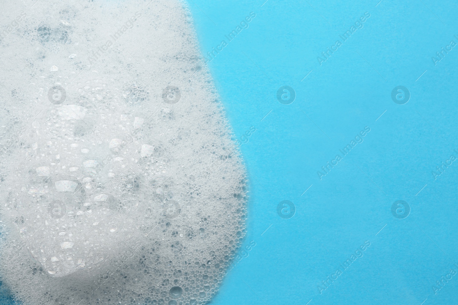 Photo of Fluffy bath foam on turquoise background, top view. Space for text