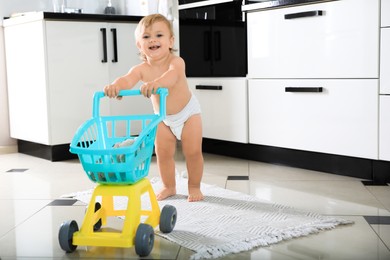 Cute baby with toy walker in kitchen. Learning to walk