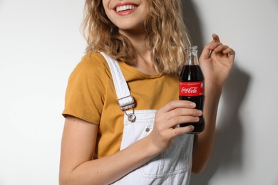 MYKOLAIV, UKRAINE - NOVEMBER 28, 2018: Young woman with bottle of Coca-Cola on white background, closeup