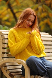 Beautiful woman sitting on bench in autumn park