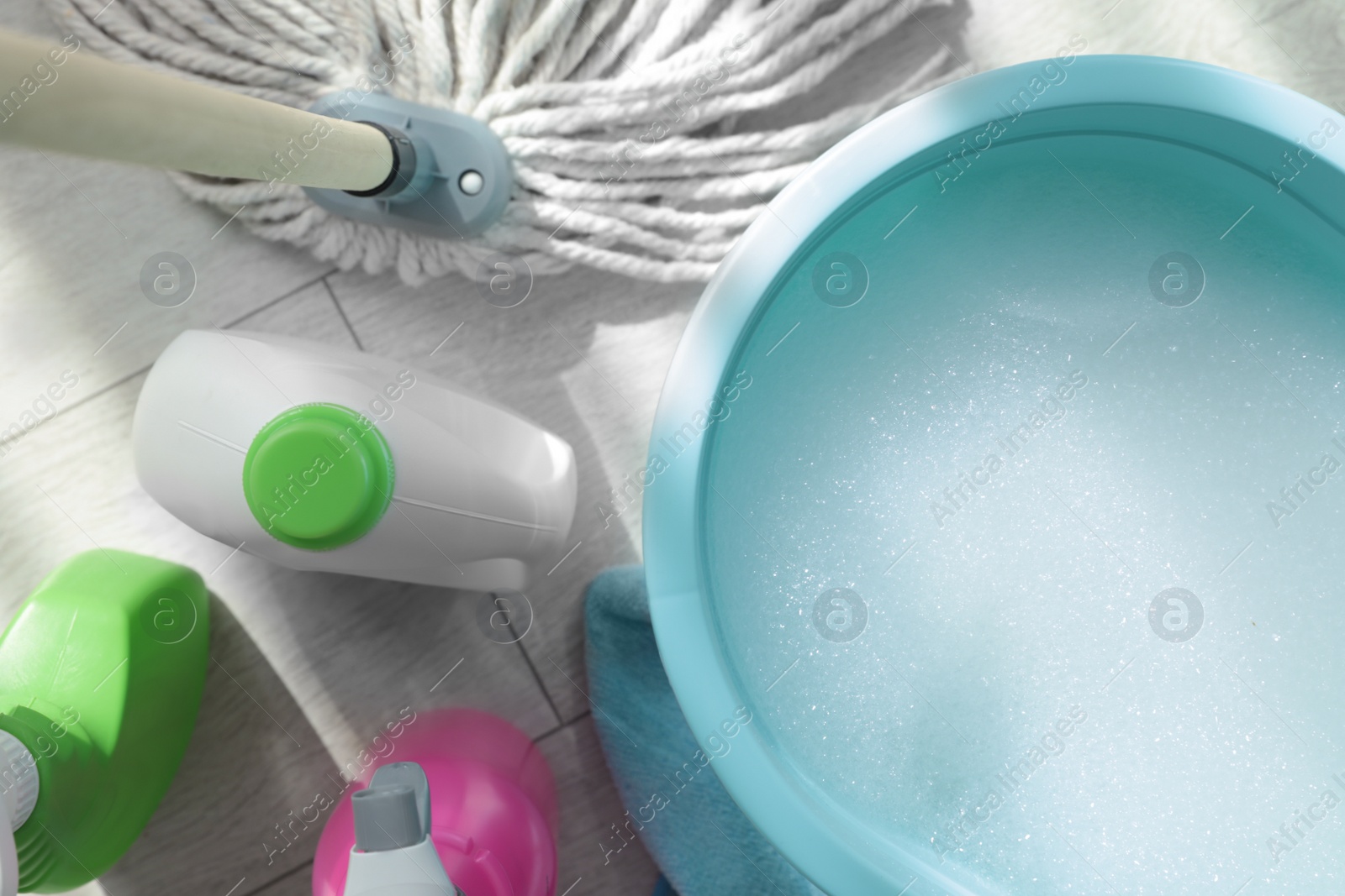 Photo of Bucket, mop and different cleaning supplies on floor, flat lay