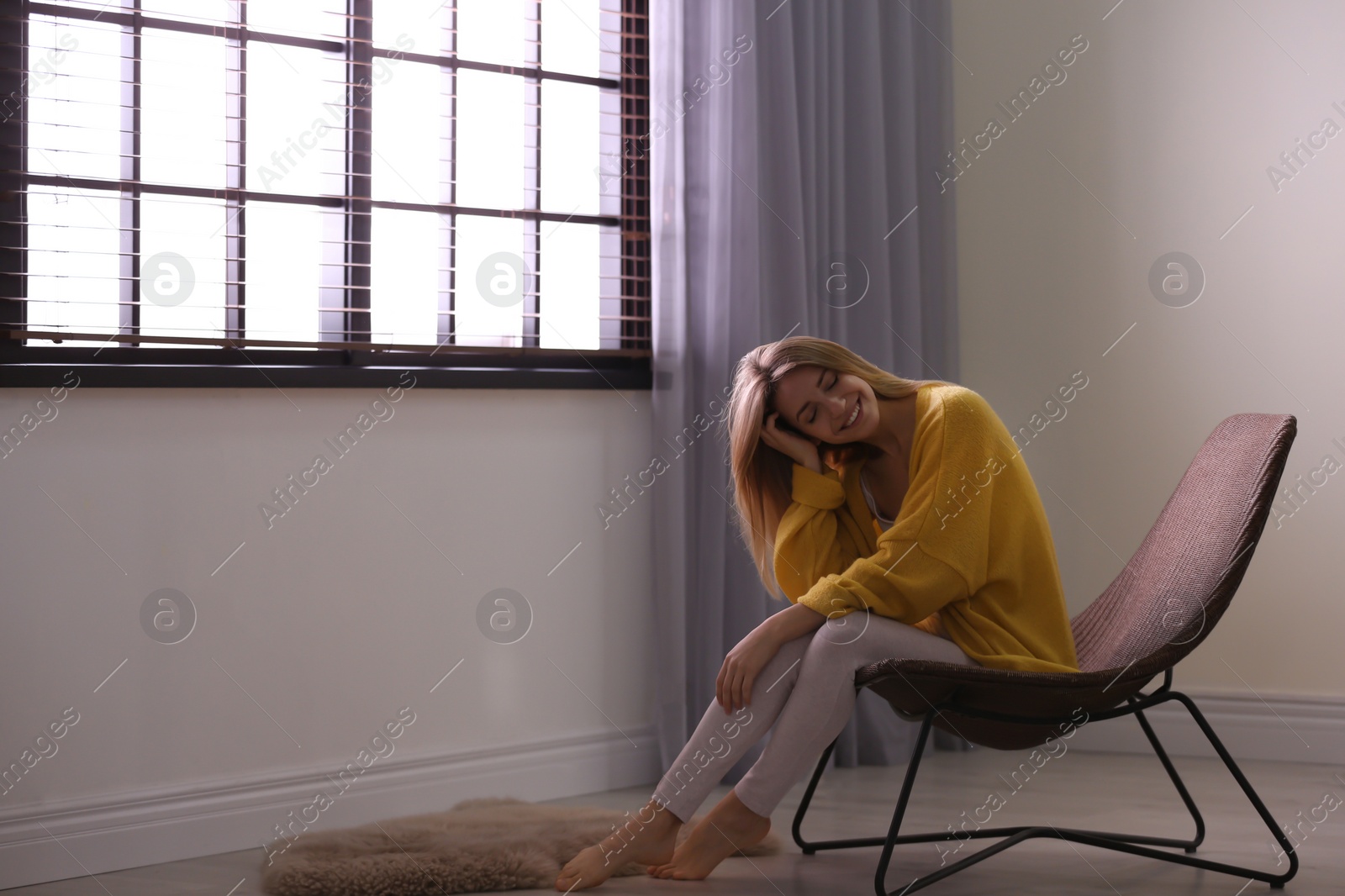 Photo of Young woman relaxing near window with blinds at home. Space for text