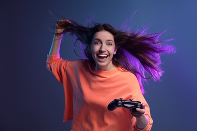 Emotional woman with game controller on dark blue background