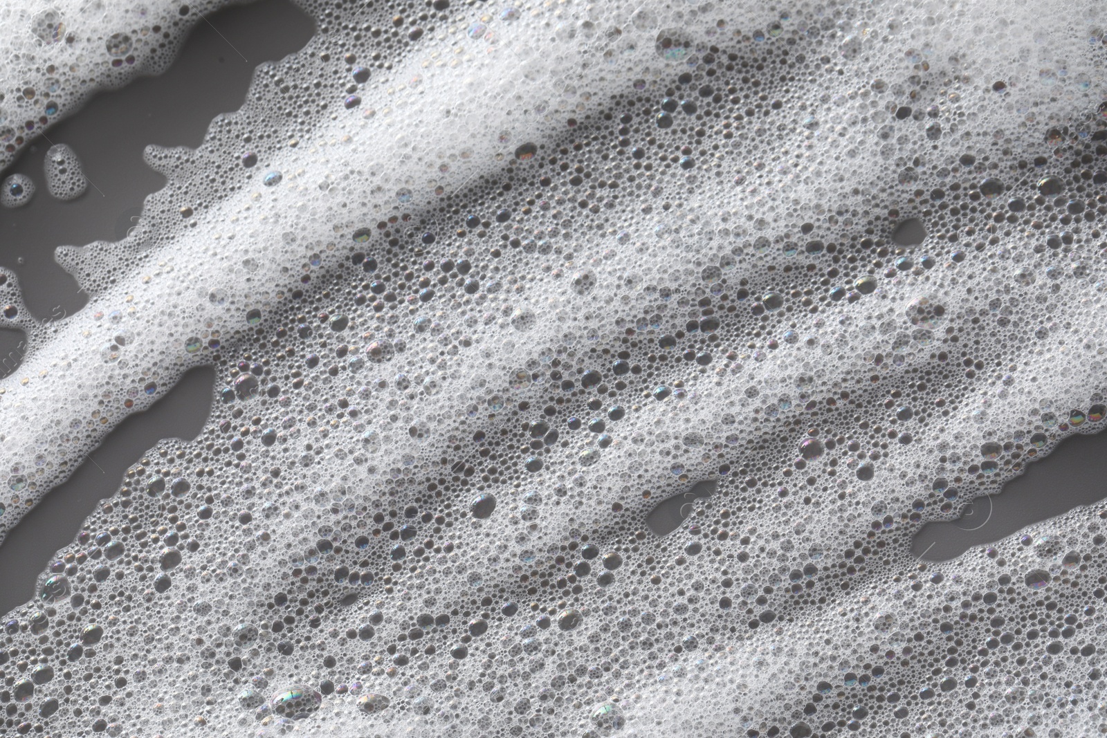 Photo of White washing foam on dark gray background, top view