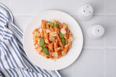 Photo of Tasty pasta with tomato sauce, cheese and basil on white tiled table, top view