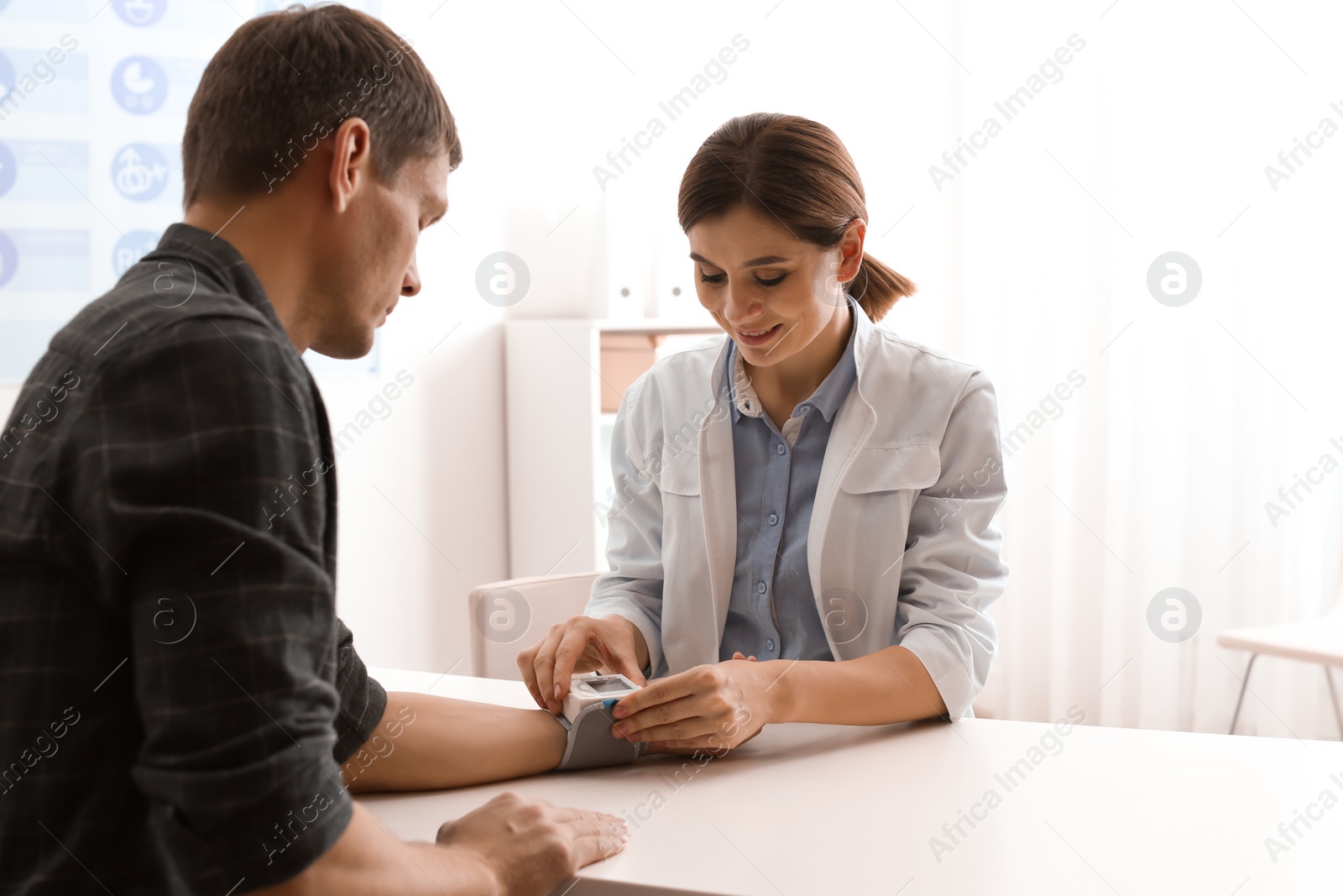 Photo of Doctor checking patient's blood pressure in hospital. Cardiology concept