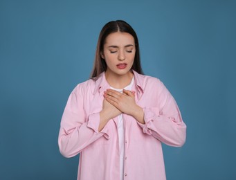 Young woman suffering from cold on blue background