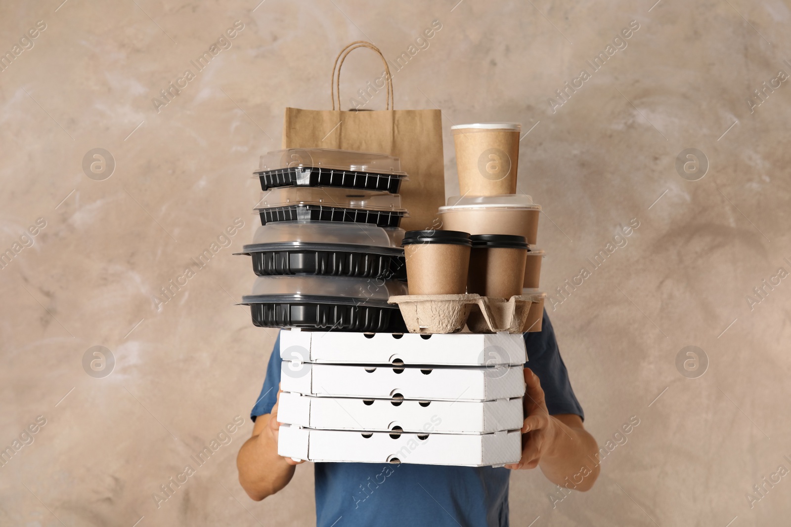 Photo of Courier with stack of orders on beige background. Food delivery service