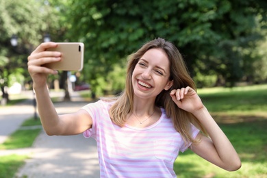 Happy young woman taking selfie in park