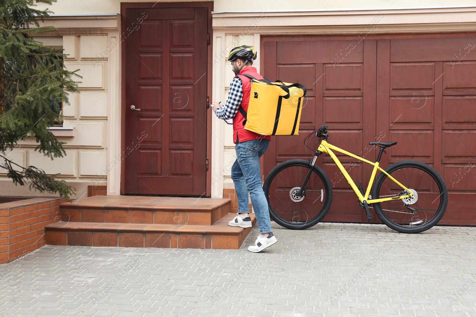 Photo of Courier with thermo bag and clipboard near customer's house. Food delivery service