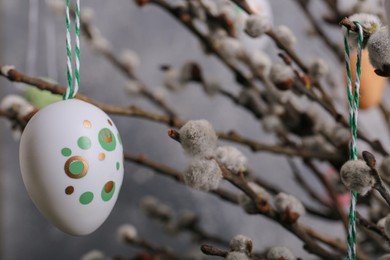 Photo of Beautiful willow branches with painted eggs on light grey background, closeup and space for text. Easter decor